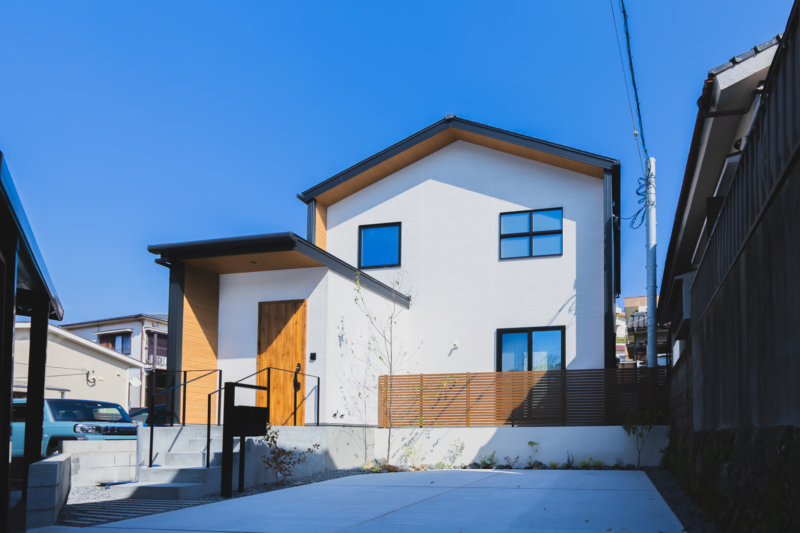 鹿児島県鹿児島市唐湊3丁目のモデルハウス 切妻屋根の家。木調のドアに軒天で白い外観でアクセント